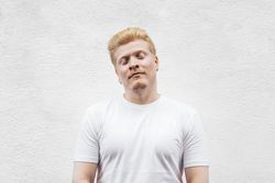 Monochrome: Portrait of a Latino man with albinism in t-shirt against a bright background.