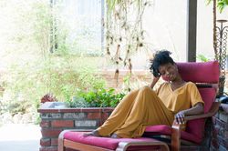 Beautiful woman relaxing in garden chair smiling and looking at camera