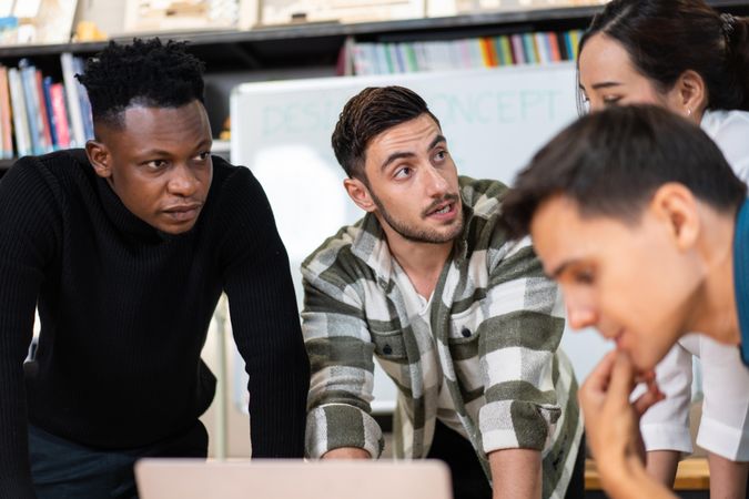 Diverse colleagues leaning over desk working on project