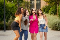 four smiling friends pointing upward and looking in that directi