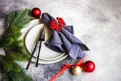 Christmas table setting with snowy pine branch, baubles and holly