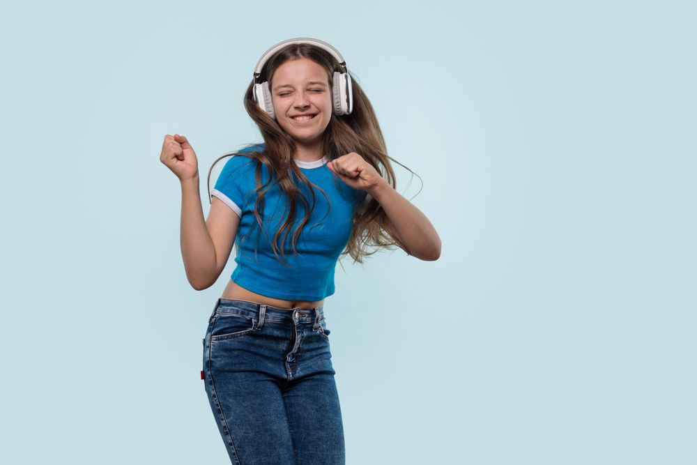 Girl wearing headphones dances joyfully while listening to music.