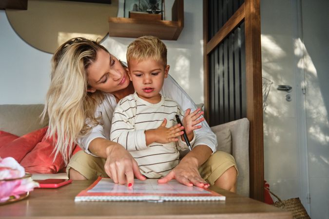Little boy learning reading with mother at home