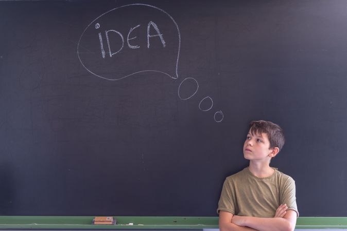 Boy standing at board with "idea" in thought bubble written in chalk