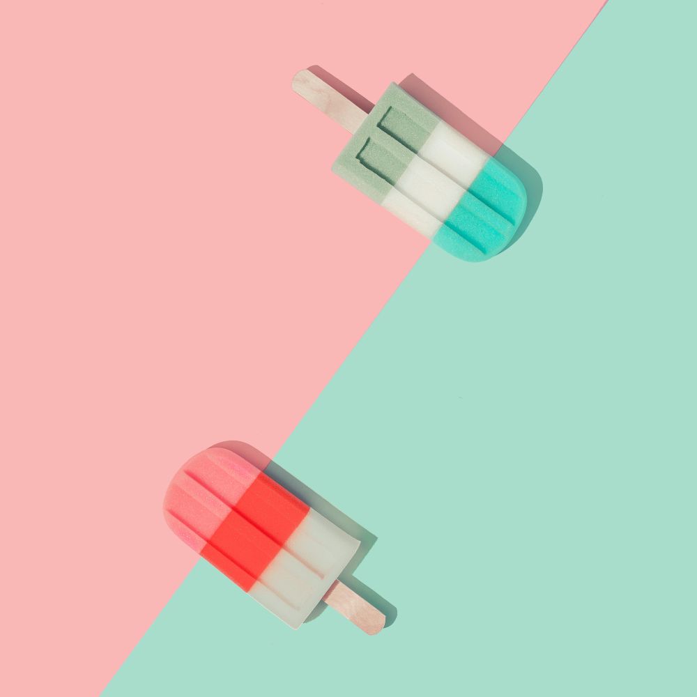 Ice cream popsicles in pastel pink and blue colors on paper duotone background