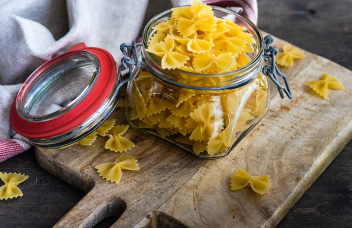 Farfalle pasta in glass jar on wooden board