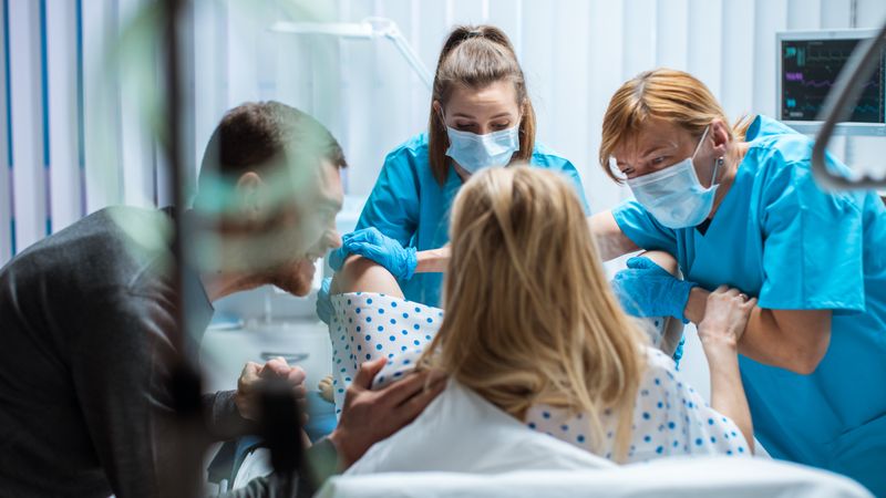 In the Hospital Woman Giving Birth, Husband Holds Her Hand in Support