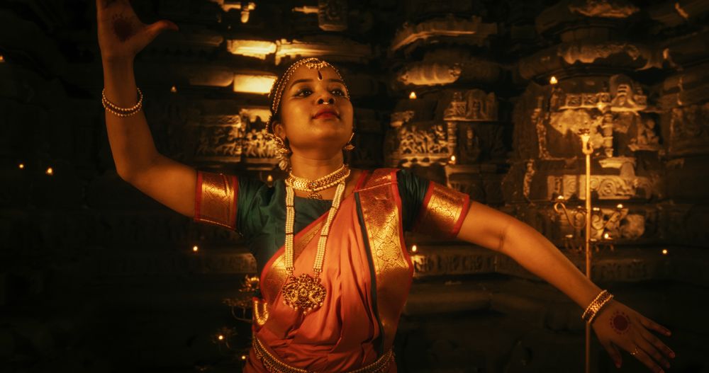 Dynamic Shot of Indian Woman in Traditional Clothes Dancing Bharatanatyam in Colourful Sari While Looking at the Camera.