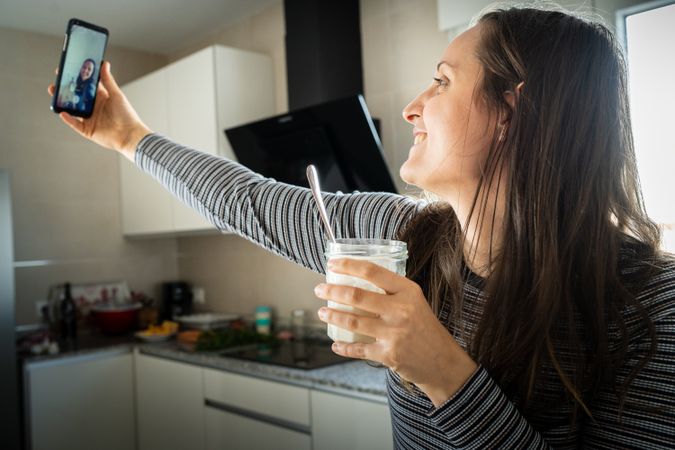 Cheerful woman taking selfie with yogurt