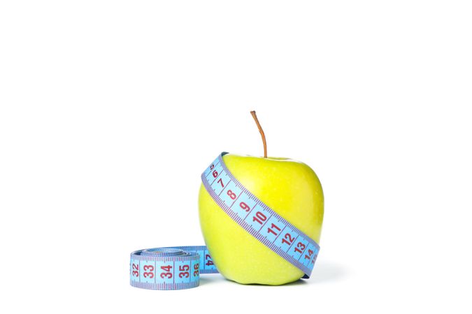 Measuring tape and apple isolated on plain background
