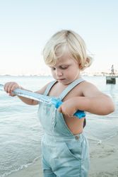 Cute curious toddler investigating soap bubble toy on sea resort