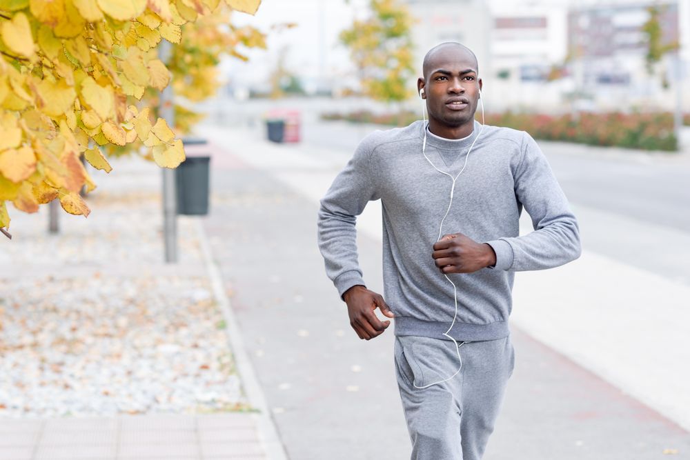 Male jogging in city during fall with autumn trees in background