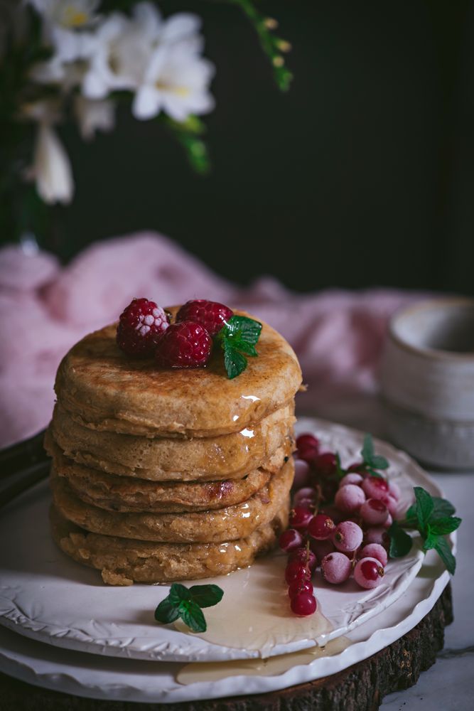 Pile of raspberry pancakes with honey on plate