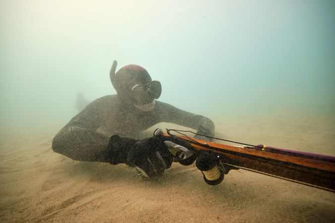 Diver with speargun fishing undersea under