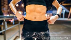 Woman in sportswear showing muscular abs at night with city background 4mWdQv