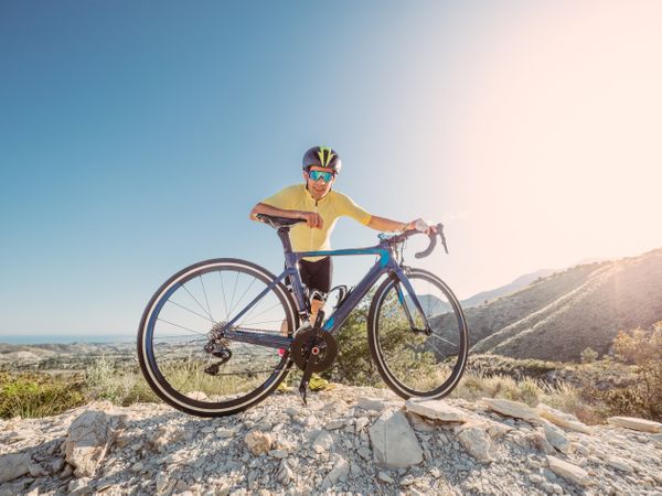 man resting and enjoying the views while riding a bicycle on a mountain road