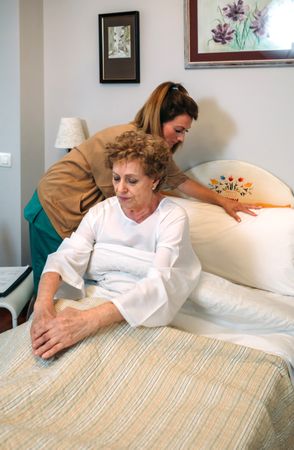 Caregiver accommodating pillow to older patient