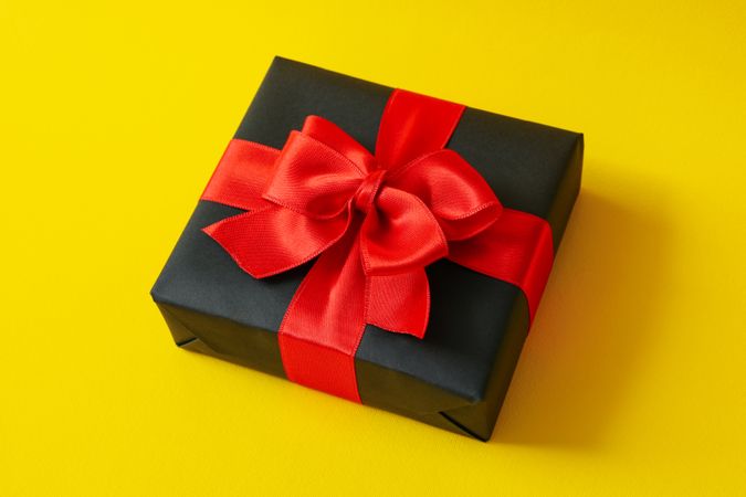 Gift box with red bow on yellow background