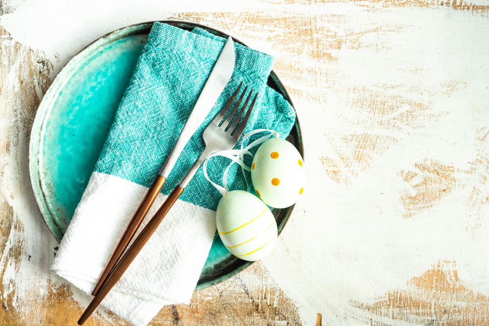 Top view of Easter table setting with ceramic teal plates and spotted Easter eggs