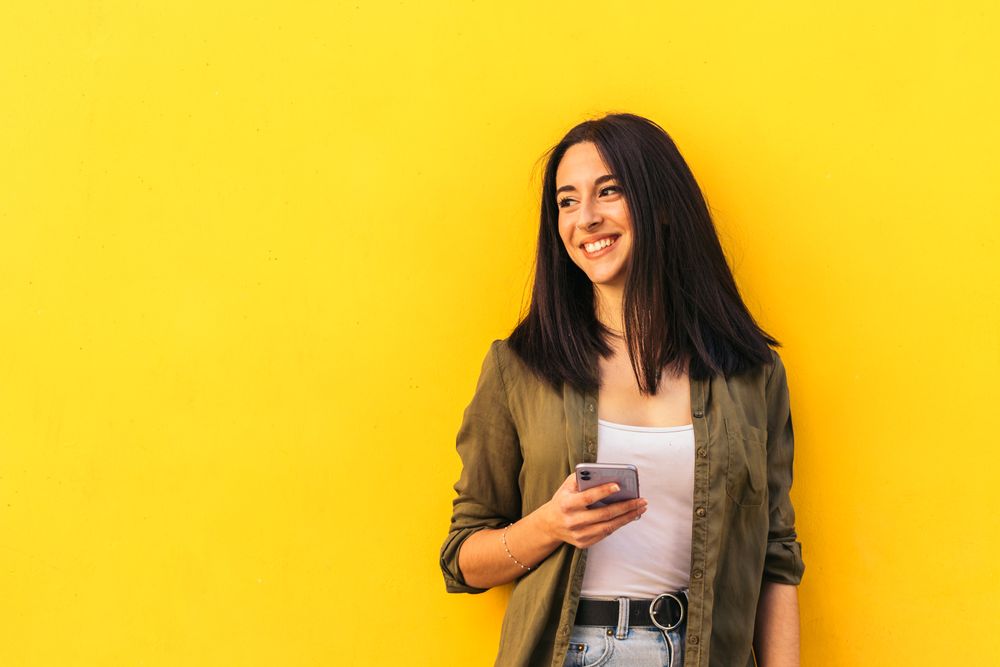 young stylish woman using her mobile and looking aside