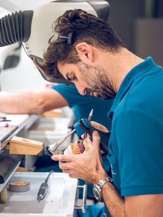 Technician man carving implant teeth on jaws fixed in articulato