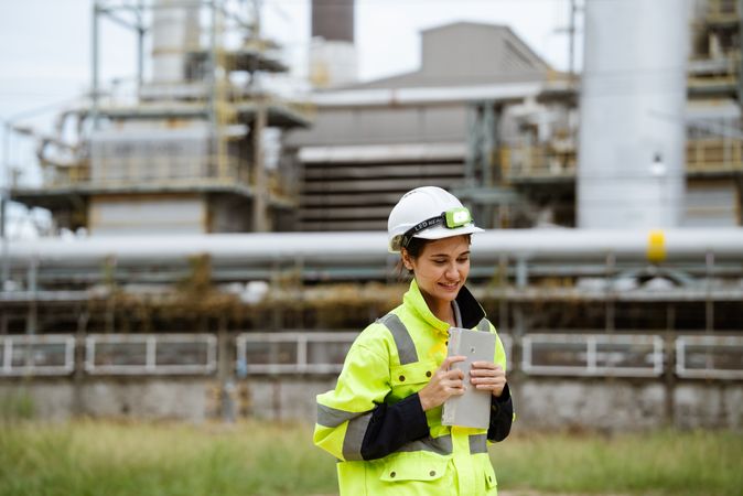 Female engineer in protective uniform with digital tablet at refinery oil factory