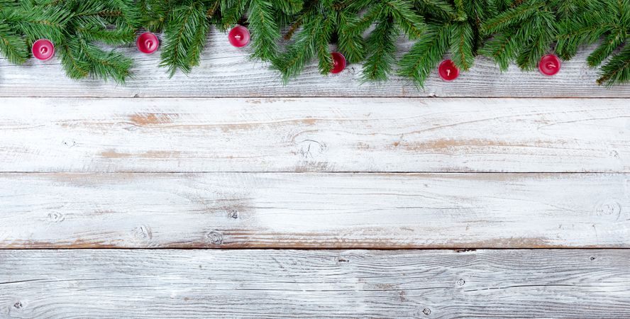Christmas evergreen branches and red candles on vintage wooden planks
