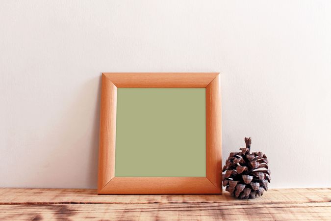Plain square wooden picture frame with green interior leaning against wall mockup