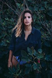 Stylish woman in green vegetation looking at camera