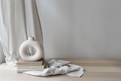 Modern organic shaped vase with old books on folded drapery