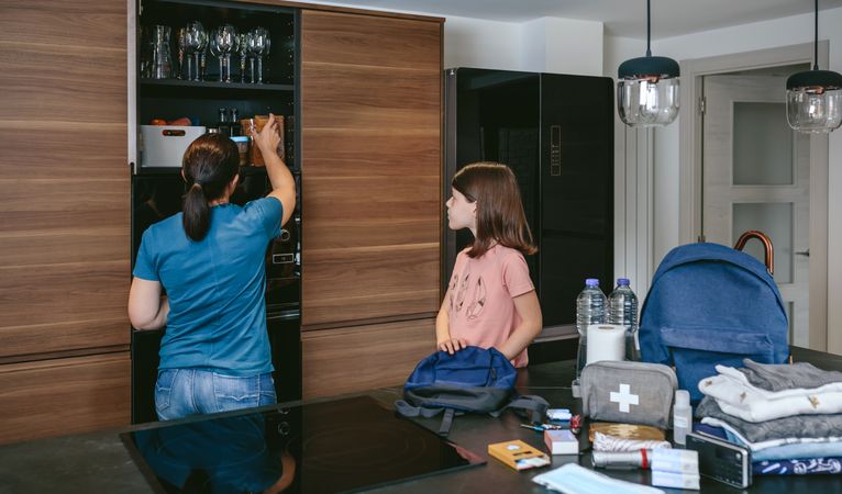 Mother preparing emergency backpack with her daughter