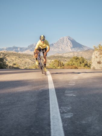 healthy man riding a bicycle on a mountain road in a sunny day