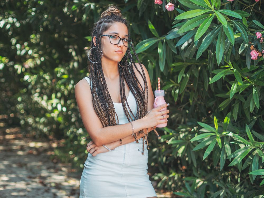 Stylish young woman with dreadlocks and beverage
