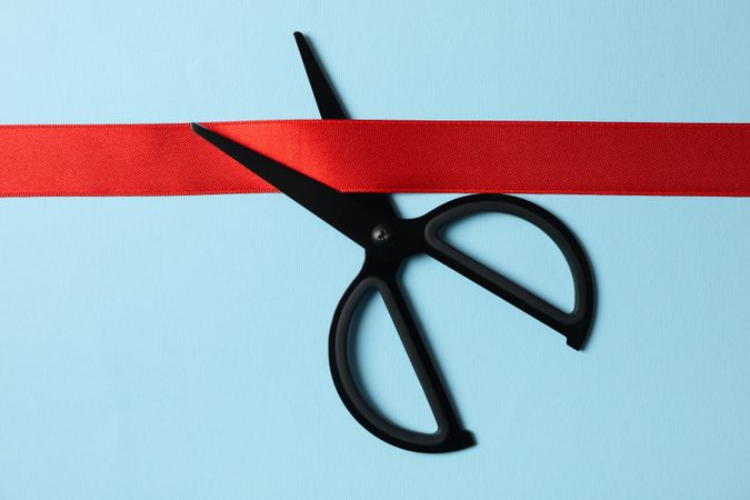 scissors and red ribbon on blue background