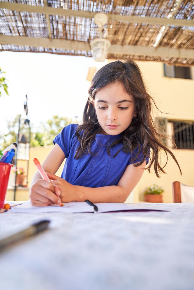 Focused girl drawing picture with felt pens