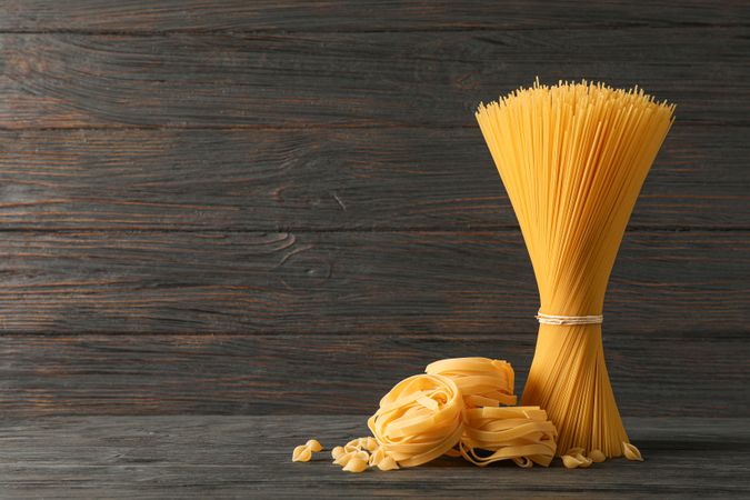 Pasta composition on wooden table, space for text. Dry raw whole pasta