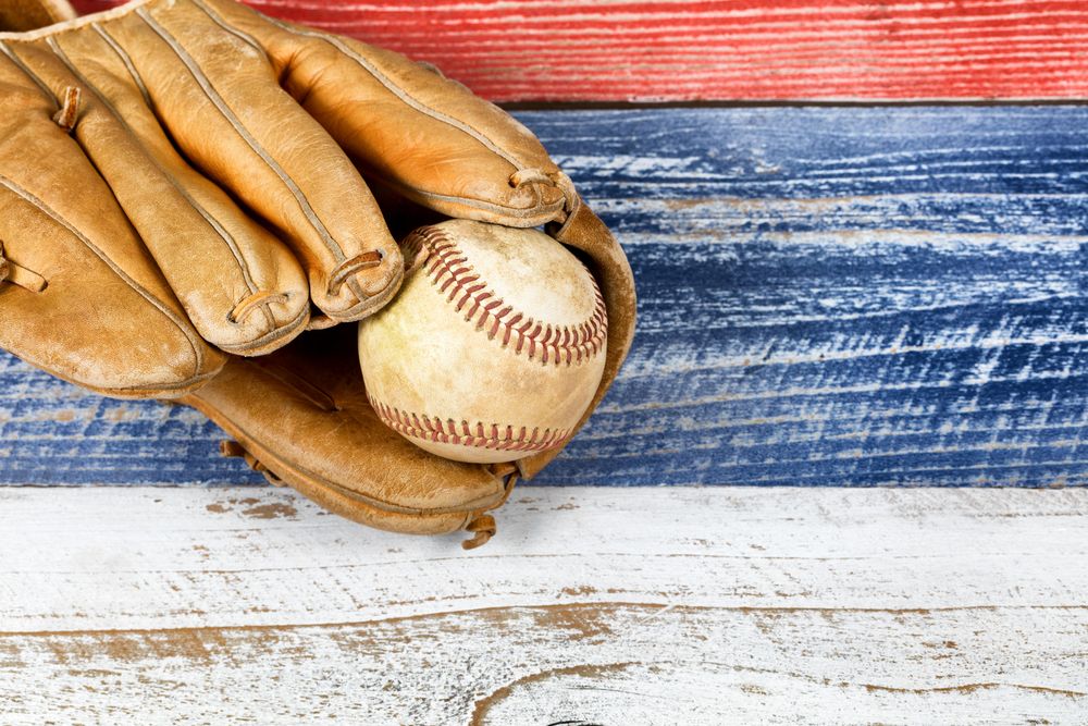 Weathered baseball mitt and ball on faded boards painted in American national colors
