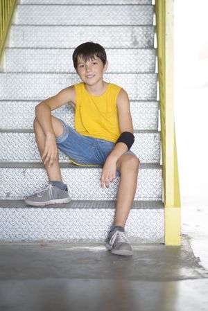 Teen boy in yellow sitting on steps