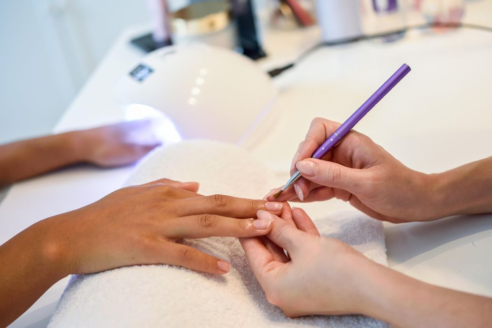 Woman having nail varnish applied by a professional