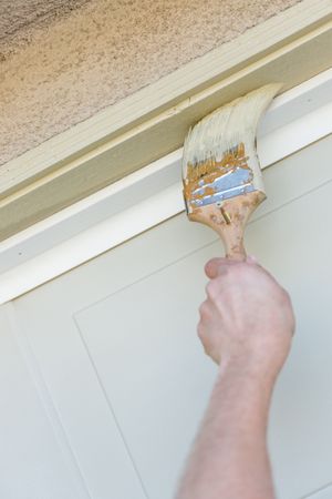 Professional Painter Cutting In With Brush to Paint Garage Door Frame