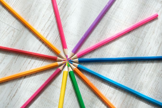 Coloured pencils arranged in a circle on a wooden background
