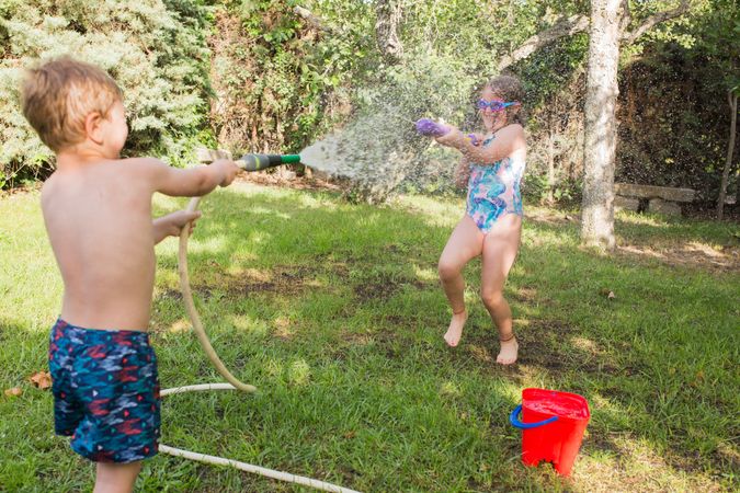 Little kids in swimwear having fun with splashing water