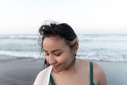 Portrait of a young Hispanic woman posing relaxed in front of the sea at the beach