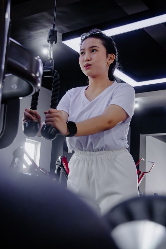 Focused young woman exercising on a machine at the modern fitnes