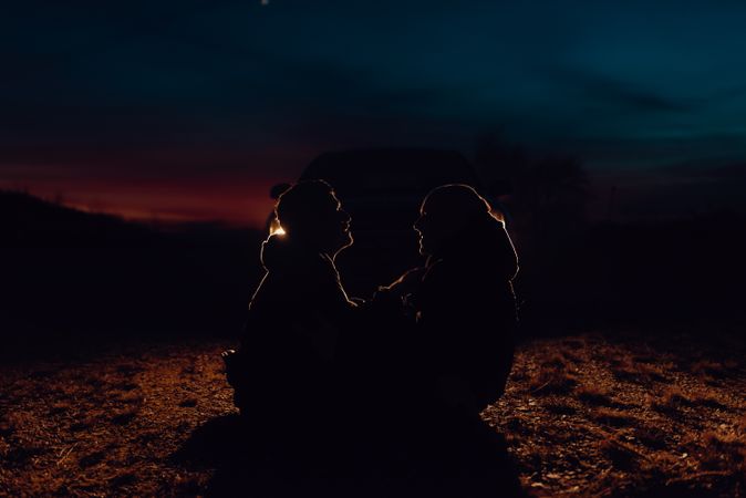 Men hugging and sitting on ground on field at night