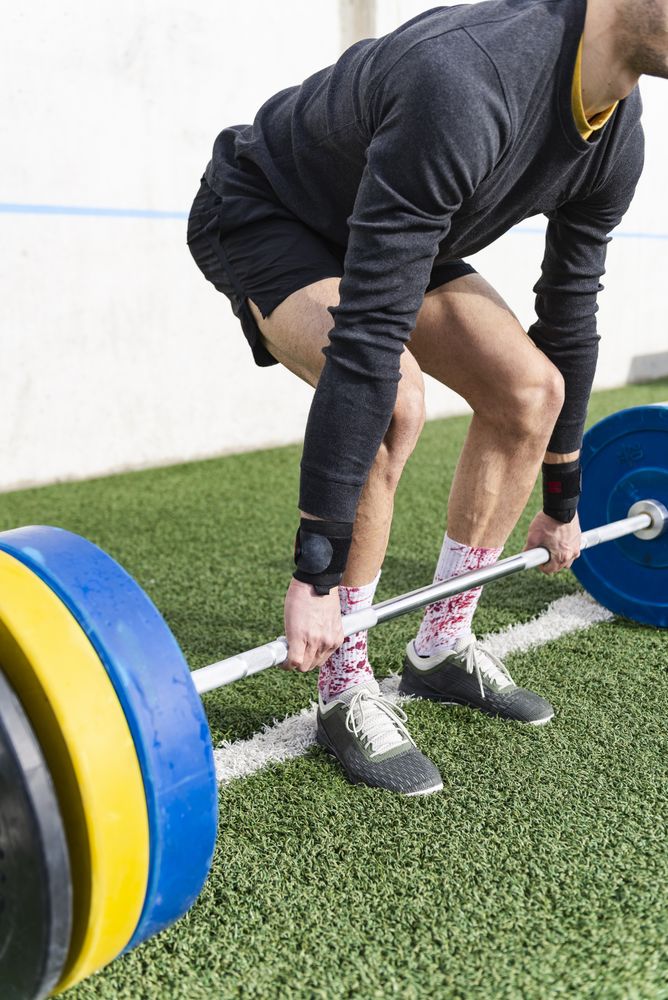 Man training with barbell on sports ground