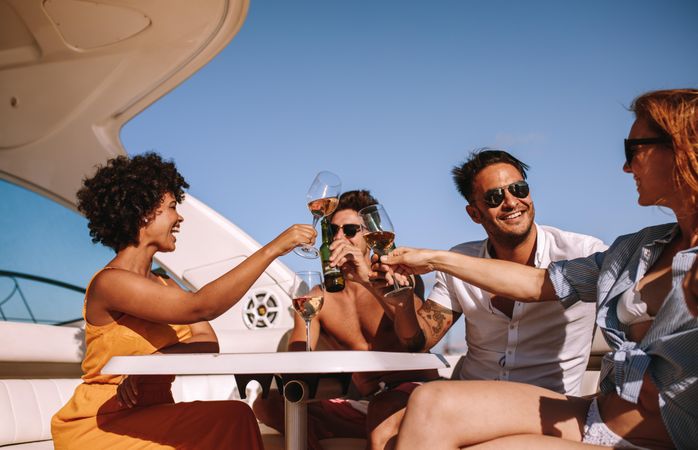 Group of friends toasting with drinks on yacht