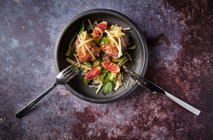 Pig trotter with figs and vegetables with greenery on plate
