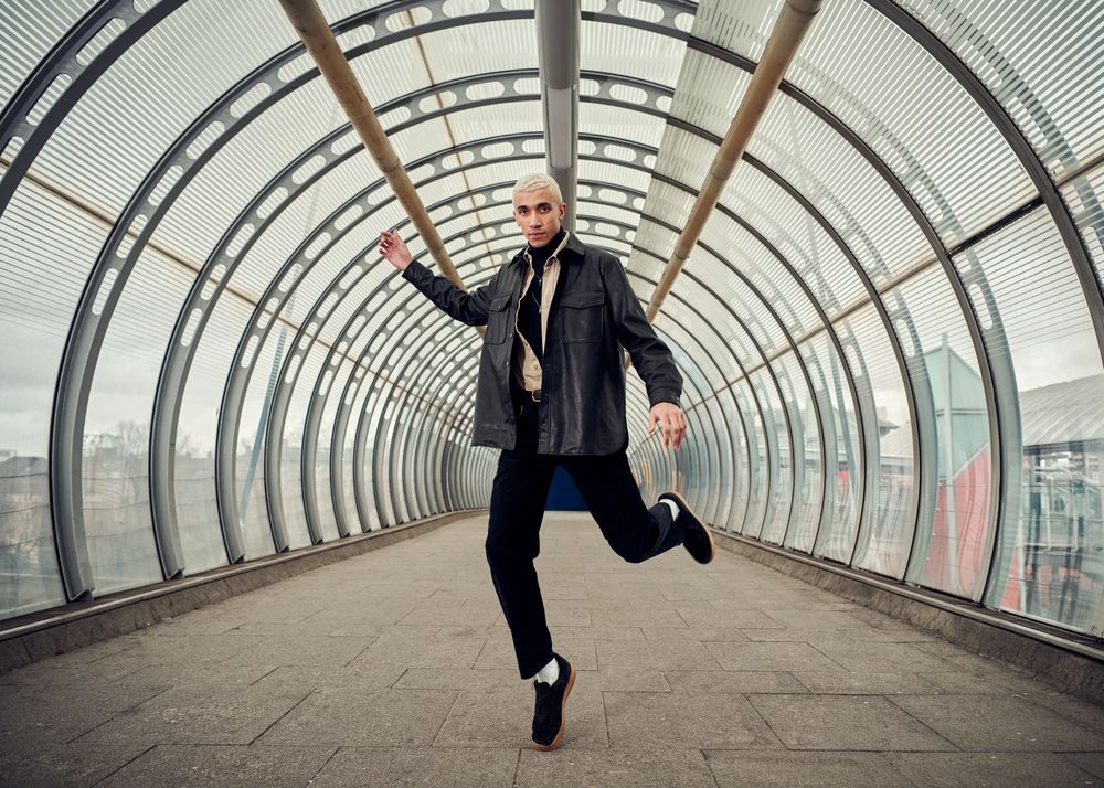 Fashionable young man in motion dancing in public walkway