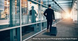 Business traveler pulling suitcase in modern airport terminal 0y1NW0